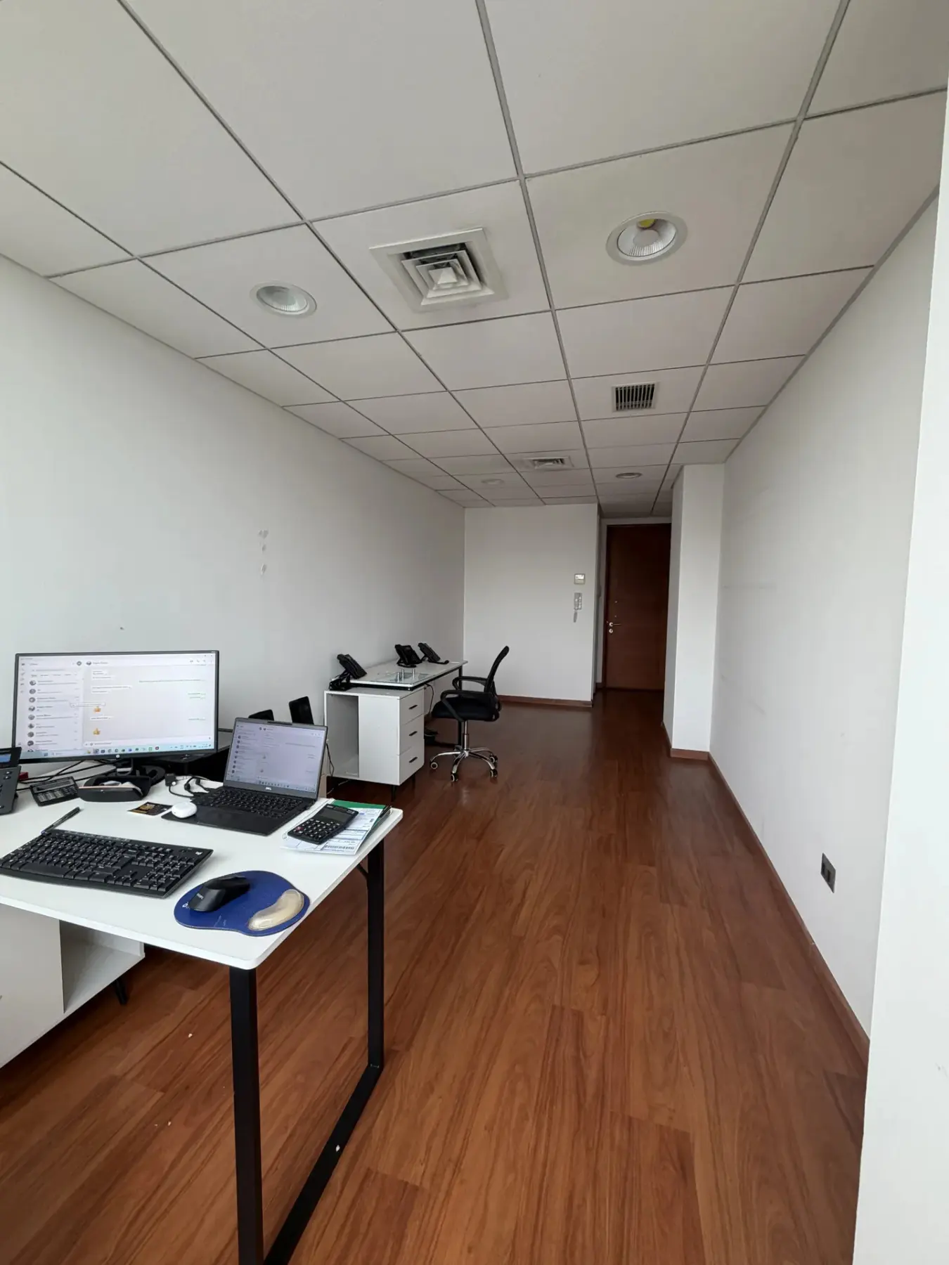 Interior de la oficina con escritorio y acceso al fondo