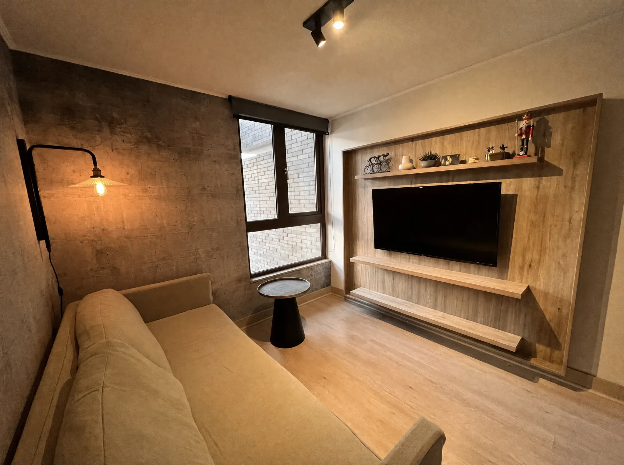Sala de estar con muro de hormigón y panel de TV en madera